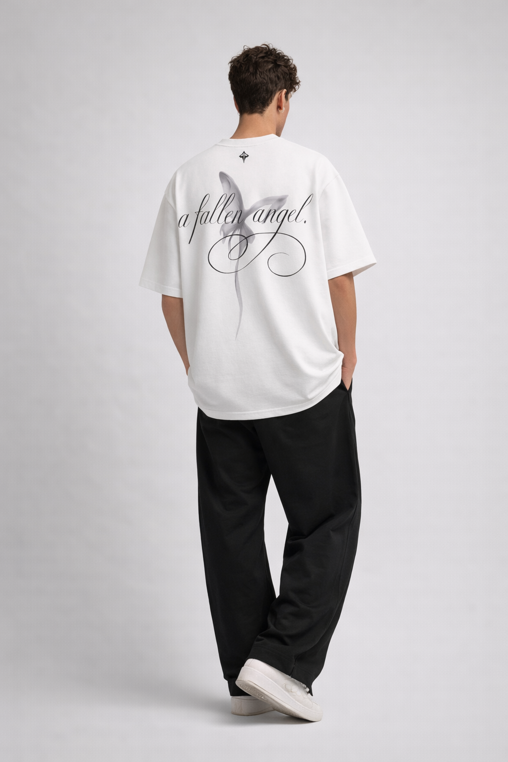 Person wearing a white t-shirt with text on the back, standing against a plain background